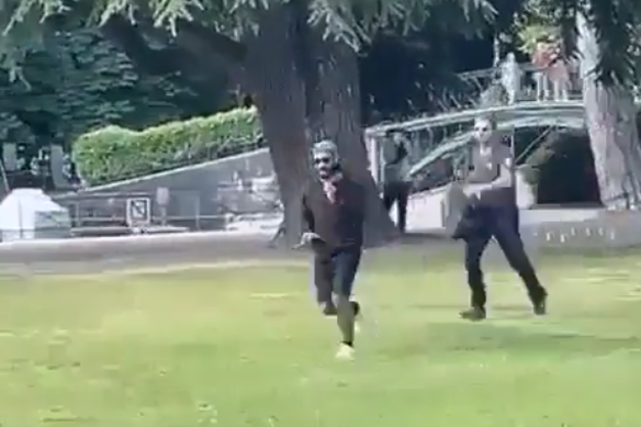 The attacker is seen brandishing a knife and being chased by a passer-by.