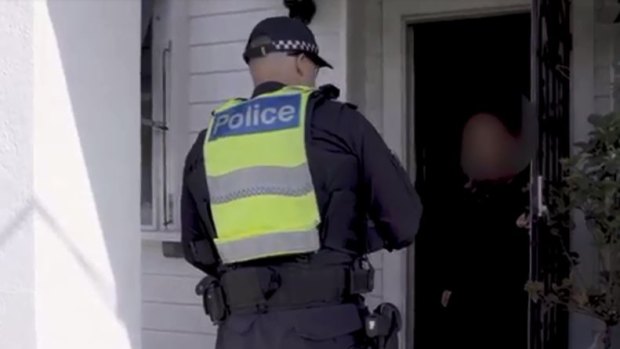 A Victorian police officer conducts a spot check on a traveller who returned from Bali in March.