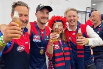 Hayden Burbank, left, and Mark Babbage, right, pictured with Demons player Alex Neal-Bullen in the Melbourne locker room after the grand final win. 