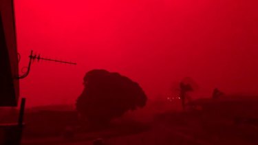 After being shrouded in darkness, the sky at Mallacoota turns an eerie shade of red as fires bear down on Tuesday morning.