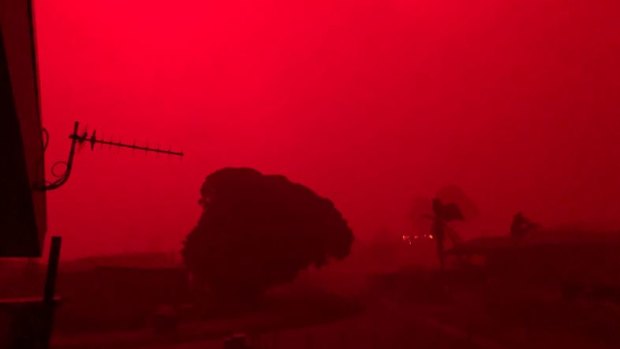 After being shrouded in darkness, the sky at Mallacoota turns an eerie shade of red as fires bear down on Tuesday morning.