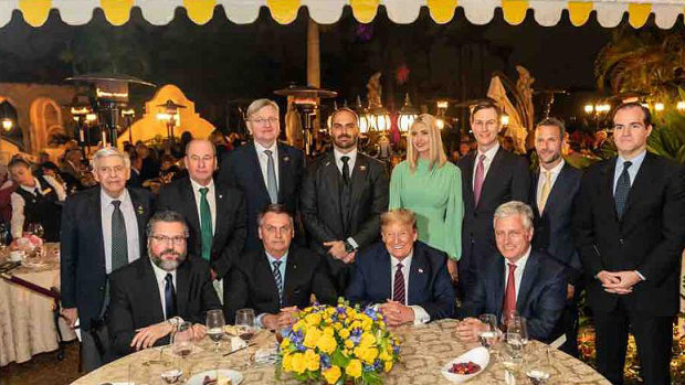 US President Trump hosts a working dinner for Brazilian President Jair Bolsonaro, seated second from left, and his delegation. The Brazilian ambassador, Nestor Forster, standing behind Bolsonaro, has also tested positive for coronavirus.