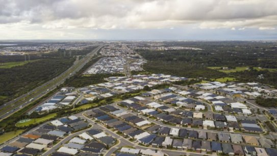 A sea of black rooves can be seen from the sky extending along the freeway.