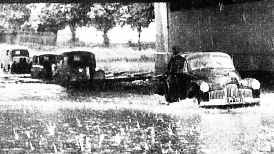 Cars plough through flood waters under the Alexandra Street bridge in South Yarra.