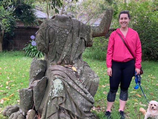 Look no hands: Emma Monger and dog Henry-James with Britannia’s torso behind a garden wall at a private garden in Hornsby Shire.