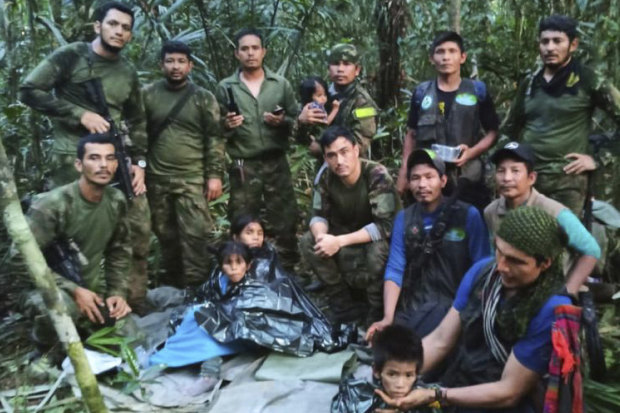 In this photo released by Colombia’s Armed Forces Press Office, soldiers and indigenous men pose for a photo with the four indigenous children who were missing after a deadly plane crash.