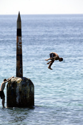 Boys jump off the pylon at Cottesloe beach.