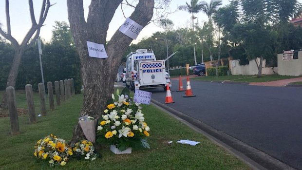 Floral tributes for Dr Zeng in Delfin Drive on Wednesday His home has a yellow fence and a blue SUV in the driveway.