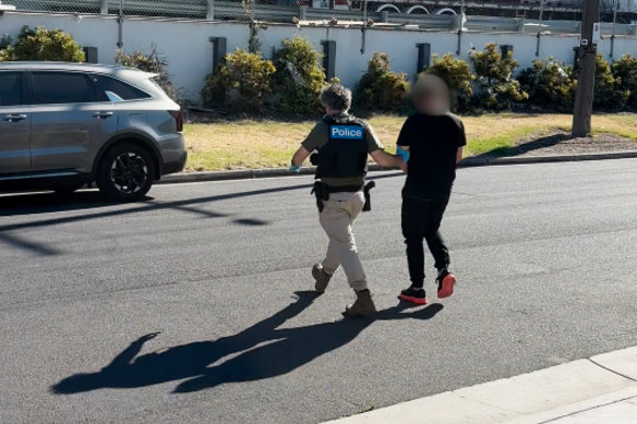 A police officer leads Waleed Haddara towards a car after he was arrested at an Altona gym on Tuesday.