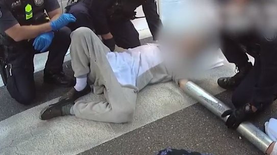 Queensland police work to remove protesters who have secured themselves in place with metal cylinders.