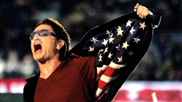 U2 lead singer Bono shows the Stars and Stripes of the US flag on the inside of his jacket during the band’s halftime Super Bowl XXXVI performance.