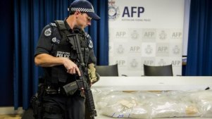 28kg: An armed police officer stands guard over one of the ACT's largest drug seizures of ice in 2014.
