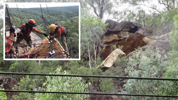 Specialist crews work to secure the boulder above the rail line at Glenbrook.