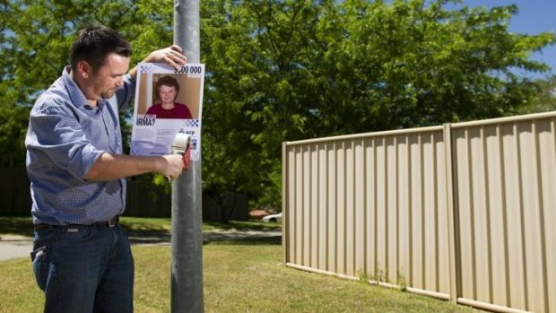 Plea for help: John Mikita puts up posters close to the McKellar home in which his grandmother Irma Palasics was killed.