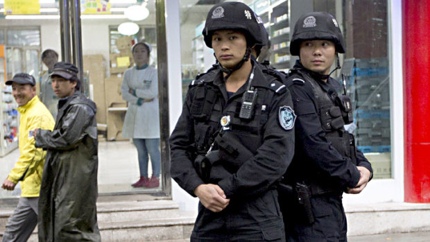 People walk past armed policemen standing guard near the site of an explosion in Urumqi, northwest China's Xinjiang region.