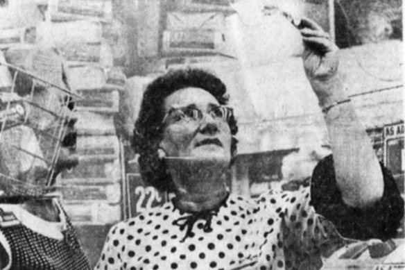 A shop assistant in Bourke Street holds up a $10 note to the light to check its authenticity.
