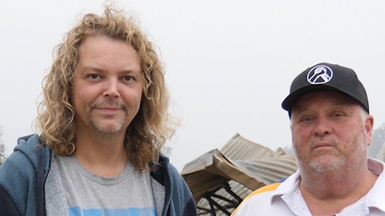 Kyle Moser, right, and his partner David Wilson, in front of the ruins of their Cobargo home.