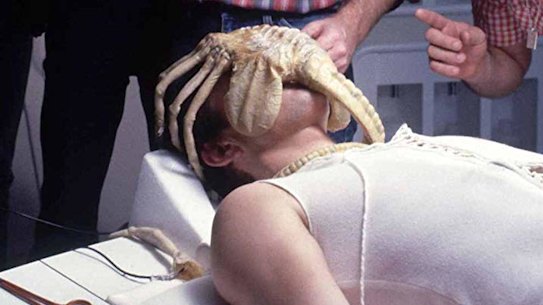 Ridley Scott (with beard) directs a scene featuring teh creature in "facehugger" form.