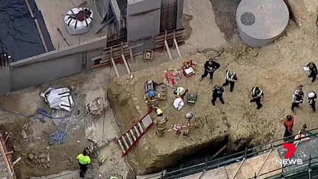 The crane dropped its load of concrete into a pit where three men were working.