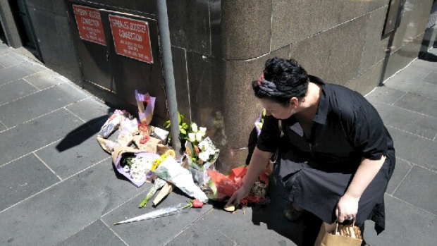 Grace Beyer lays a stone at a floral tribute on Bourke Street.