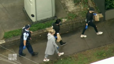 A woman was escorted by police from the scene, with her hands in evidence bags.