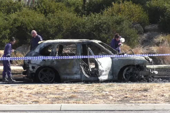 Police examine the wreck of the stolen Porsche the shooters are believed to have used.