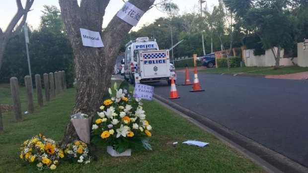 Floral tributes for Dr Zeng in Delfin Drive on Wednesday His home has a yellow fence and a blue SUV in the driveway.