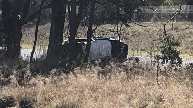 A car rests on its side after a crash at the Tuggeranong Parkway southbound off-ramp onto Hindmarsh Drive.