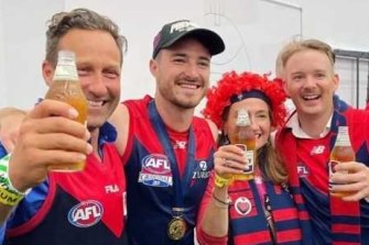 Melburnians Hayden Burbank, left, and Mark Babbage, right, pictured with Demons player Alex Neal-Bullen, were questioned by police after allegedly breaking restrictions to travel to the grand final in Perth.
