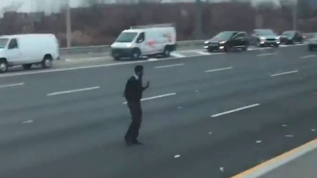A man picks up dollar notes that spilled on a New Jersey highway.