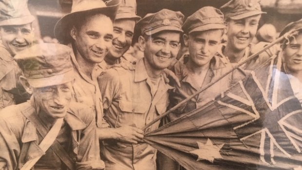 Wal Williams, second from right, with the flag patched together by soldiers.