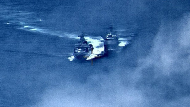 A Russian destroyer, left, sails very close to the USS Chancellorsville, right, in the Philippine Sea.