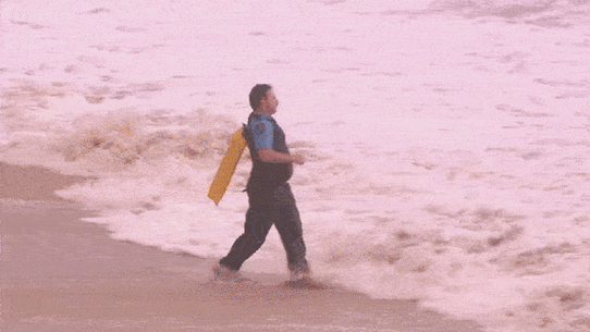 A police officer and another rescuer dive into the ocean at Coogee Beach.