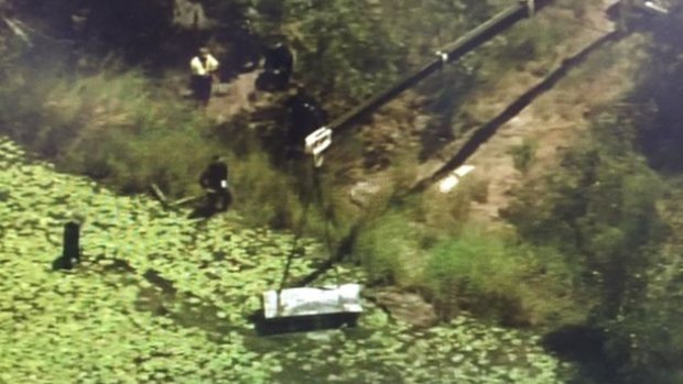 A crane lifts the metal toolbox containing the two bodies from a lagoon in Logan.