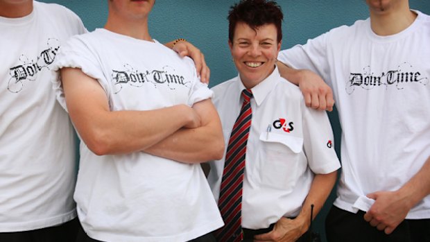 Anne Hooker, Youth Development Officer at Port Phillip Prison, with some of the inmates modelling T-shirts they print and sell.
