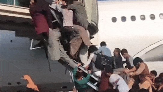 Men climbing the exit ramps to get onto a plane at Kabul airport.