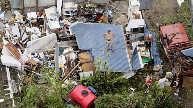 In this photo a resident stands on his roof after Cyclone Larry destroyed his property in Innisfail in March 2006.