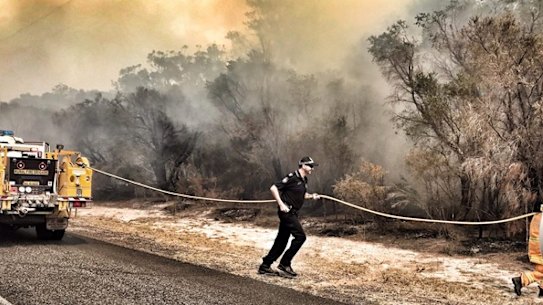 Queensland police helping firefighters run a line the fight the Kinkuna Waters bushfire, south of Bundaberg, on Friday.