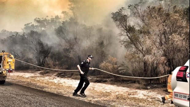 Queensland police helping firefighters run a line the fight the Kinkuna Waters bushfire, south of Bundaberg, on Friday.