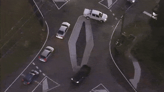 Aerial footage shows a ute doing a three-point turn to get around the diamond, while two other cars cut directly across the roundabout.