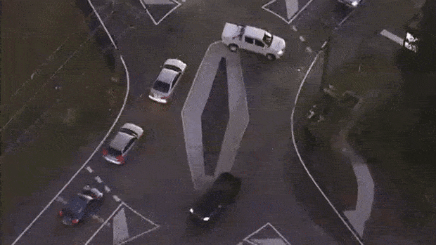 Aerial footage shows a ute doing a three-point turn to get around the diamond, while two other cars cut directly across the roundabout.