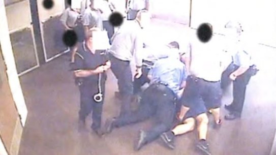 A still from CCTV footage of a young person being held on the ground in a Queensland youth detention centre, contained in a report.