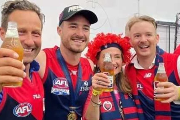 Hayden Burbank (far left), Demons player Alex Neal-Bullen and Mark Babbage (far right) inside the AFL rooms after Melbourne’s win at the grand final.