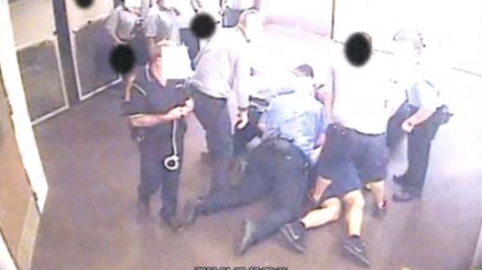 A still from CCTV footage of a young person being held on the ground was contained in a 2016 Queensland youth detention report that called for the practice to be banned.