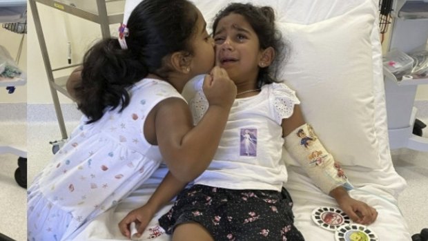 Sister Kopika comforts Tharunicaa with in hospital on Christmas Island this week before she was evacuated to a Perth hospital.