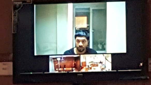 Prakash appears on a video screen during an earlier court appearance.