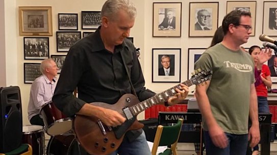 Workplace Relations, Employment and Arts Minister Tony Burke playing guitar and Veterans Affairs Minister Matt Keough singing in the Labor Party caucus room in the band Left Right Out.