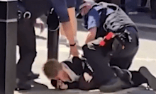 A crowd of people watched on as the woman who allegedly stabbed multiple people was detained by police.