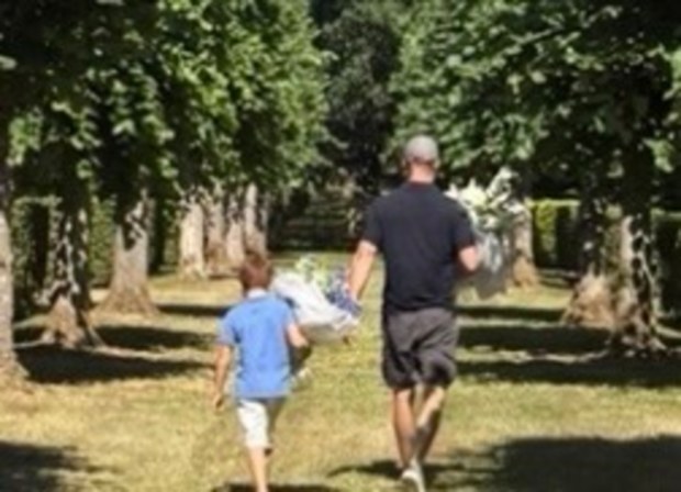 A close-up photo shared by Meghan, Duchess of Sussex, shows Prince Harry and Prince Archie carrying bouquets of flowers during which is thought to be a visit to Princess Diana’s grave at Althorp.