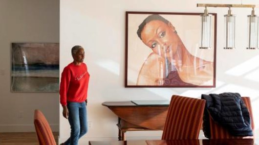 B Smith walks past a portrait of her younger self in her home.